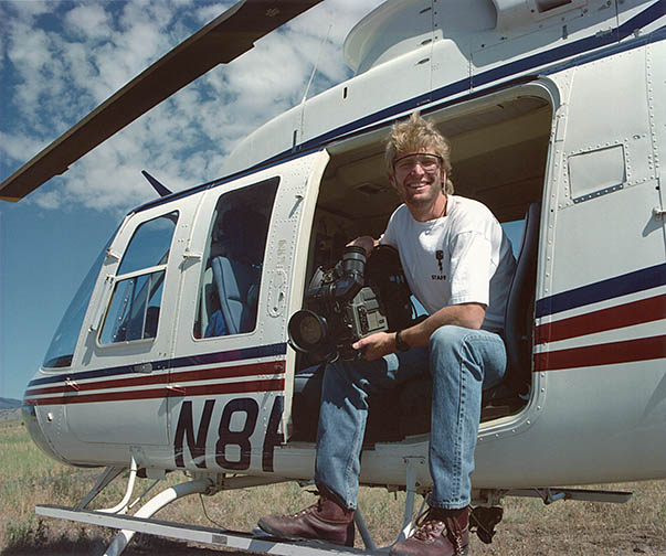 Sitting in the open door of a helicopter, photographer Dave Parsons holds a broadcast video camera after a morning of shooting aerial footage of the National Renewable Energy Laboratory in Golden, Colorado. Photo by Warren Gretz